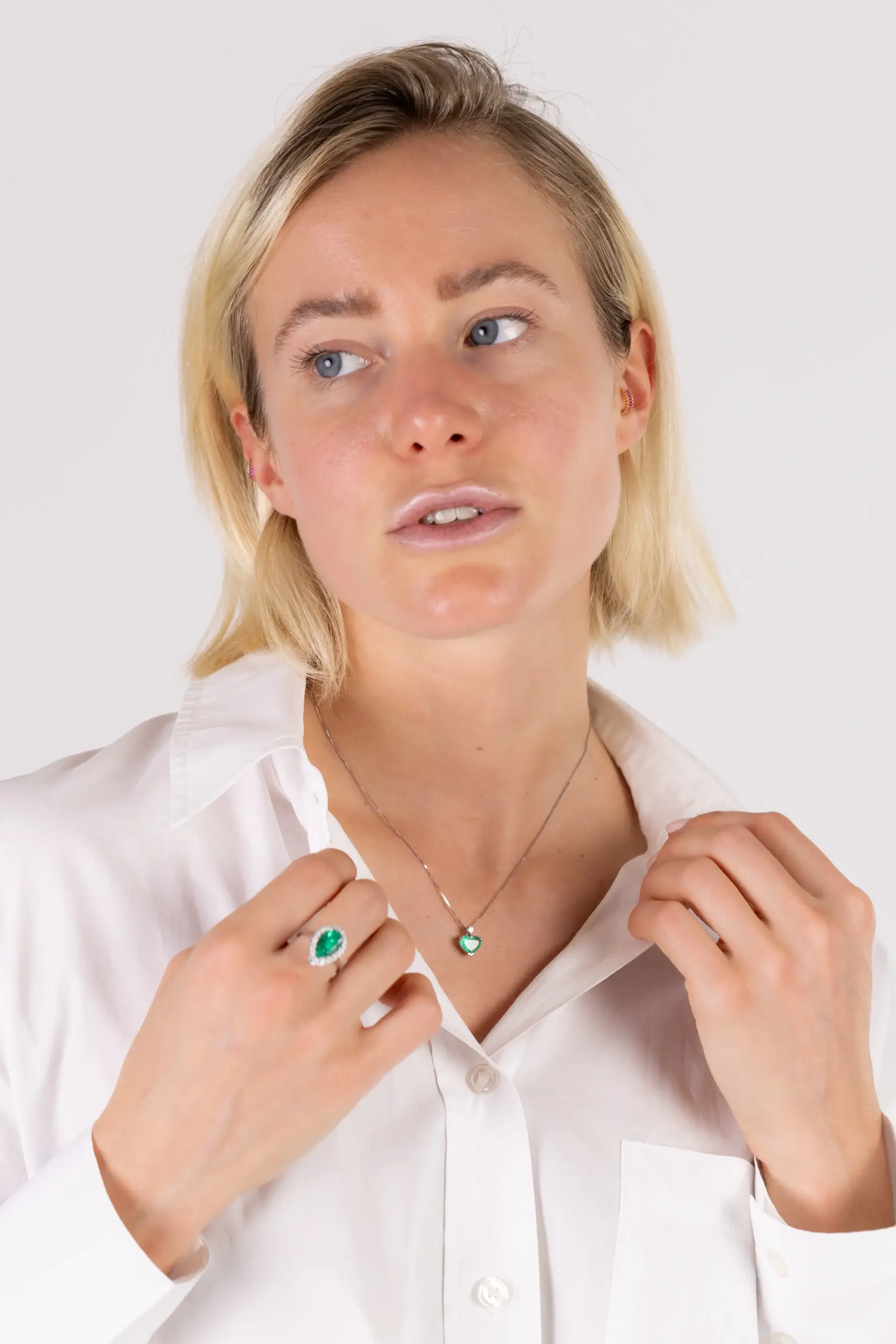 Donna che indossa anello e collana con smeraldo su camicia bianca