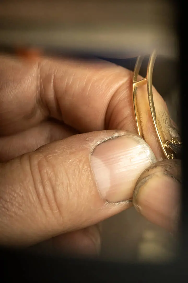 Mani lavorano un gioiello d'oro
